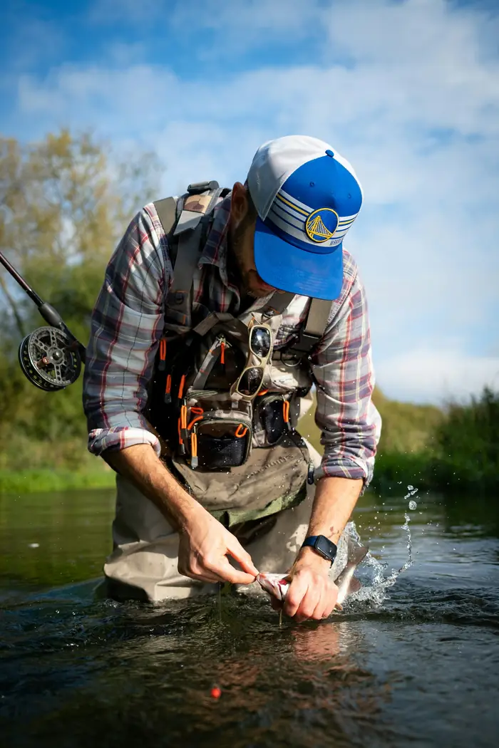 A fly fishing guide tying on a fly beside the river